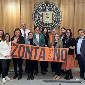 ZONTA DAYS of ACTIVISM: Members of Zonta of Malden attended a recent Malden City Council meeting and displayed their banner “Zonta Says No” against domestic violence, as part of their 16 Days of Activism. Above, they are shown with the members of the Malden City Council. At the meeting, Zonta member Maria Luise made a presentation explaining the 16 Days of Activism as well as the Silent Witness exhibit now on display in the Malden City Hall lobby. (Courtesy Photo/Zonta of Malden)