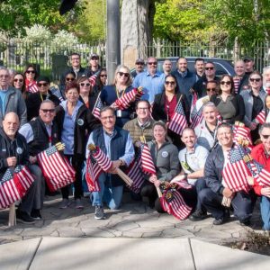 Volunteers, veterans, students, city officials, including Mayor Robert Van Campen, center, and community members gather at Woodlawn Cemetery during the annual Memorial Day flag placement.
