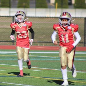 Everett Crimson Tide Pop Warner football 11-year-old Gold players Brennis McGrath and captain Ediell Diaz, from left, run off the field during last Sunday’s New England regional final against the New Haven Steelers in Worcester. (Courtesy photo)