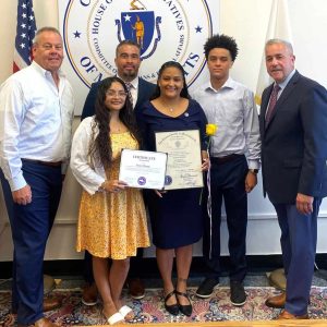 Supt. Of Everett Public Schools William Hart, left, is shown with State Representative Joe McGonagle during a presentation of a citation to Elaine Monge, Director of Human Resources and Employee Relations for Everett Public Schools, for being a 2025 Commonwealth Heroine nominee. Elaine is shown with her family during the recent presentation at Mass. State House.  (Courtesy photos)