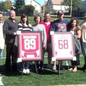 Rich Dellisola, Joe LaMonica, Joe Baldacchino, Sr. and his wife, Kathleen, Bill Marchant, Jimmy Curtis, Sr. and his wife, Adrienne, Everett Crimson Tide Pop Warner president Brian Dimond and Sal DiDomenico, from left, were on hand to honor the memory of former players Joe Baldacchino, Jr. (89, former Huskie) and Jimmy Curtis, Jr, (68, former Eagle) in 2012 at Everett Memorial Stadium. Joe passed away in 2009, and Jimmy in 2011. The league is shown presenting Joe and Brian’s framed uniforms to the respective families. (Courtesy photo)